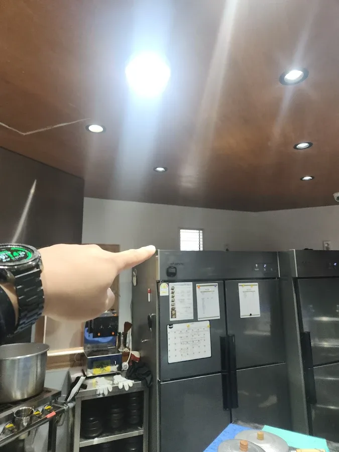 조리 공간과 냉장고가 보이는 주방에서 설치 위치를 가리키는 모습