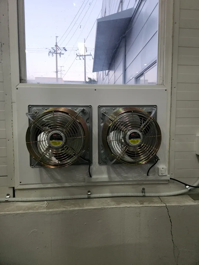 패널 안에 금속 환풍기 두 대가 설치된 창가 모습