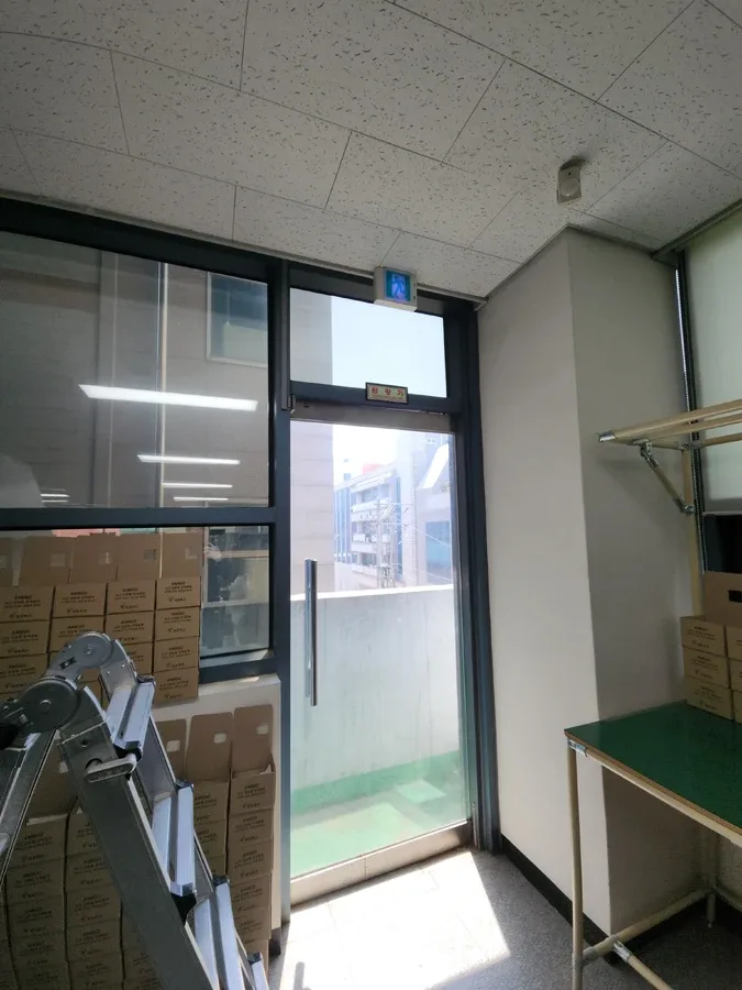 상자가 쌓인 작업 공간의 창과 발코니 쪽 유리문