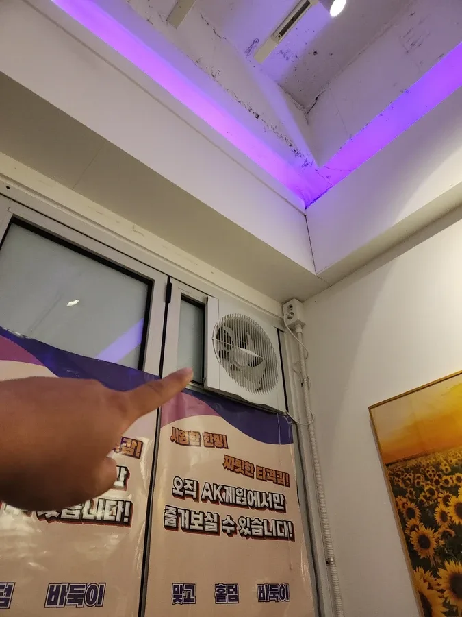 벽 상단에 환풍기 위치를 손으로 가리키는 실내 모습